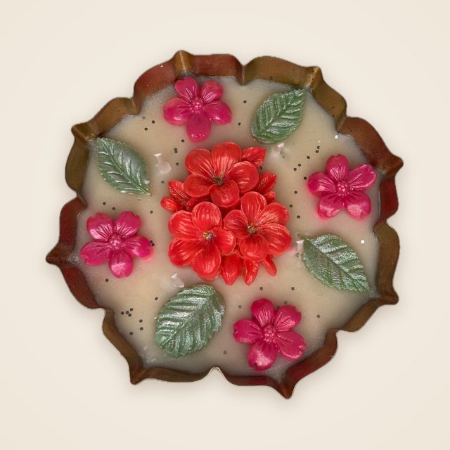 DH-07: Red and pink blooms with leaves on ivory wax, in a scalloped metal tray.