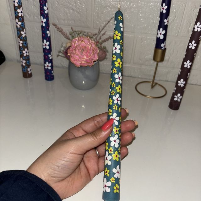 DH-18: Five hand-painted taper candles with little white flowers, one held in a hand, to show its size.
